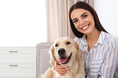 Photo of Young woman and her Golden Retriever dog in living room. Space for text