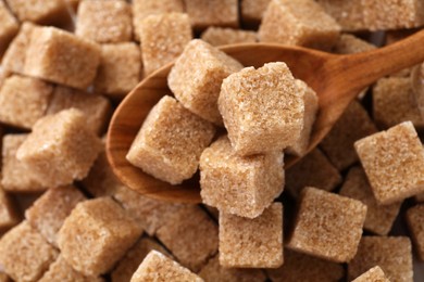 Photo of Wooden spoon on brown sugar cubes, above view