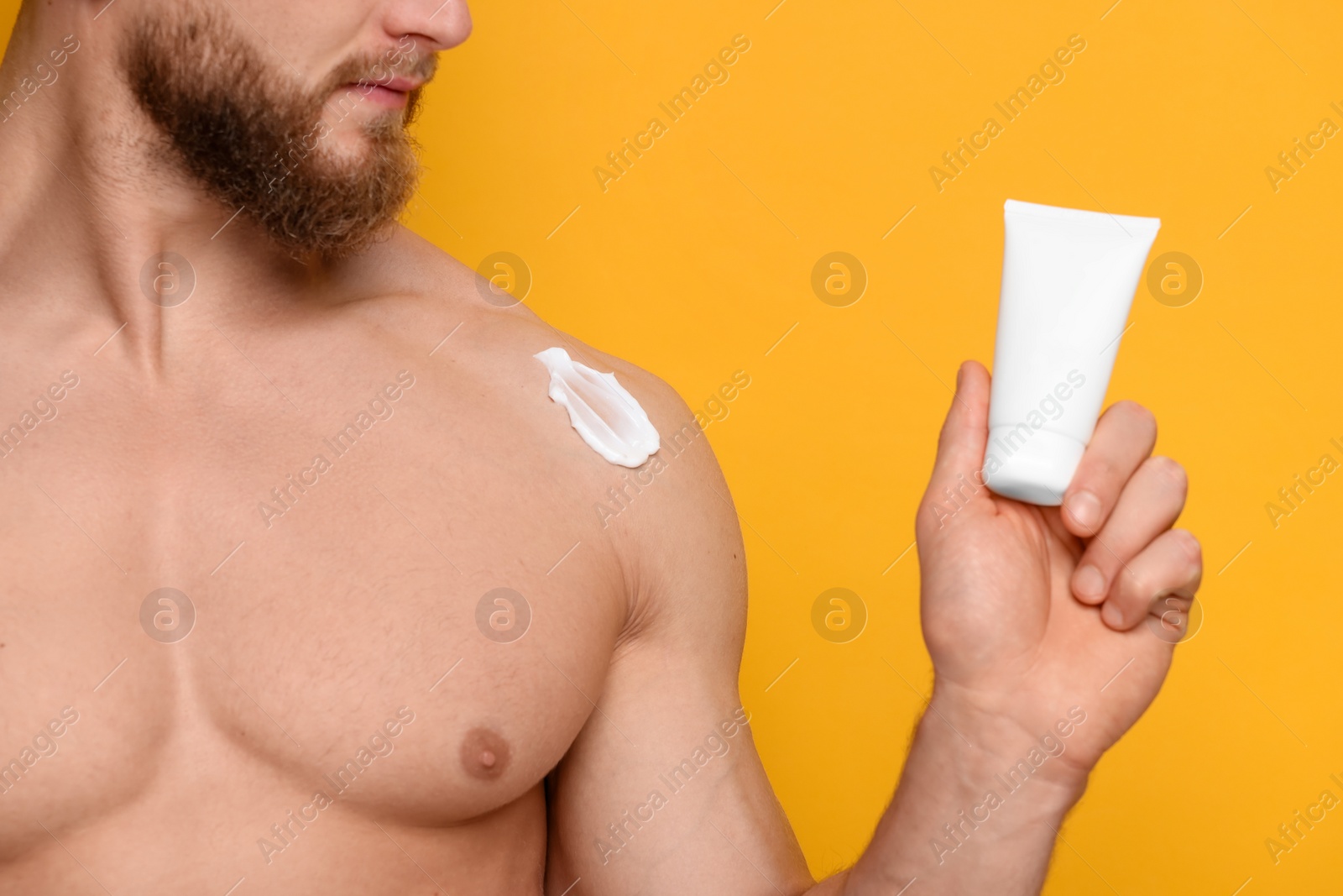 Photo of Man with moisturizing cream on orange background, closeup