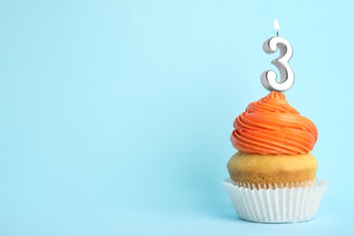Photo of Birthday cupcake with number three candle on blue background, space for text