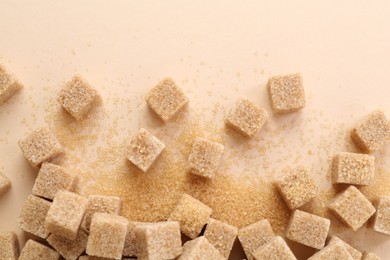 Photo of Brown sugar cubes on beige background, top view. Space for text