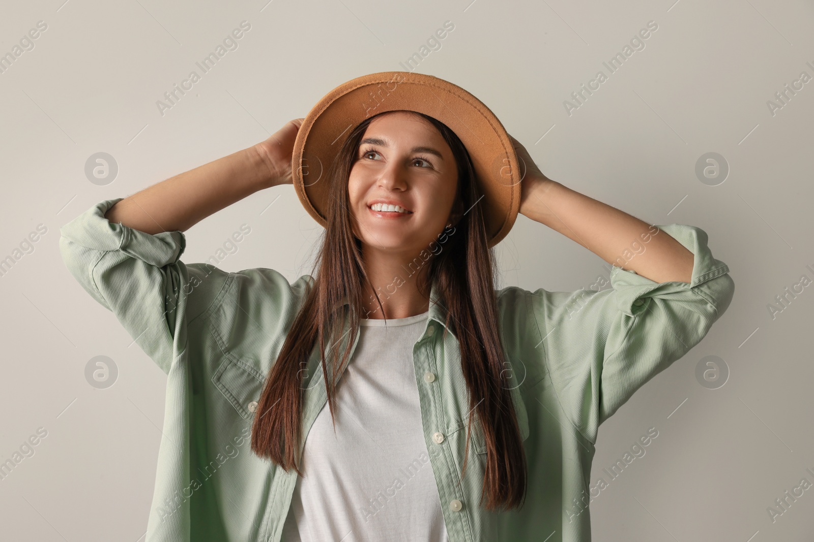 Photo of Smiling young woman in stylish outfit on light background