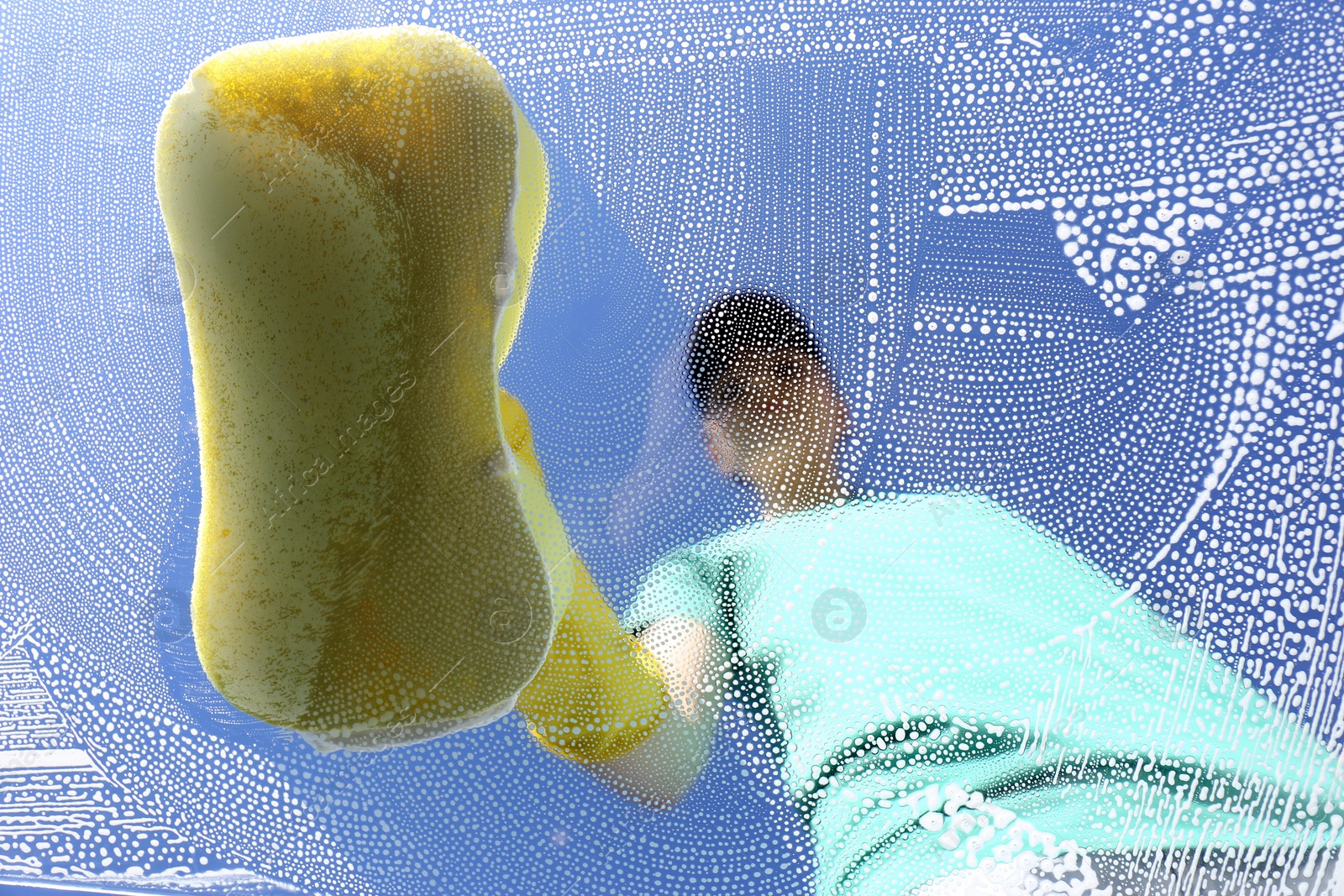 Photo of Woman cleaning glass with sponge on sunny day