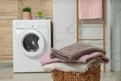 Photo of Wicker basket with laundry and washing machine in bathroom