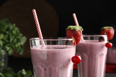 Photo of Tasty fresh milk shake with strawberry and cherry in glass, closeup
