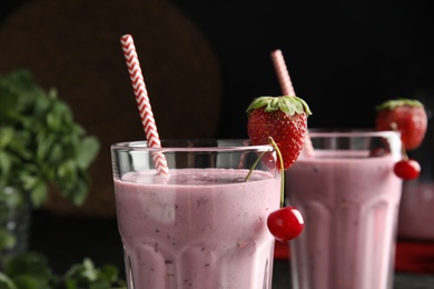 Tasty fresh milk shake with strawberry and cherry in glass, closeup