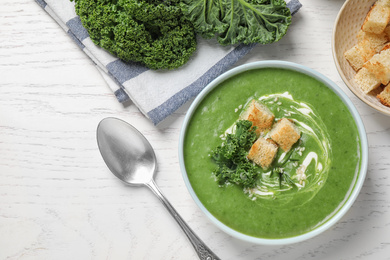 Photo of Tasty kale soup served on white wooden table, flat lay