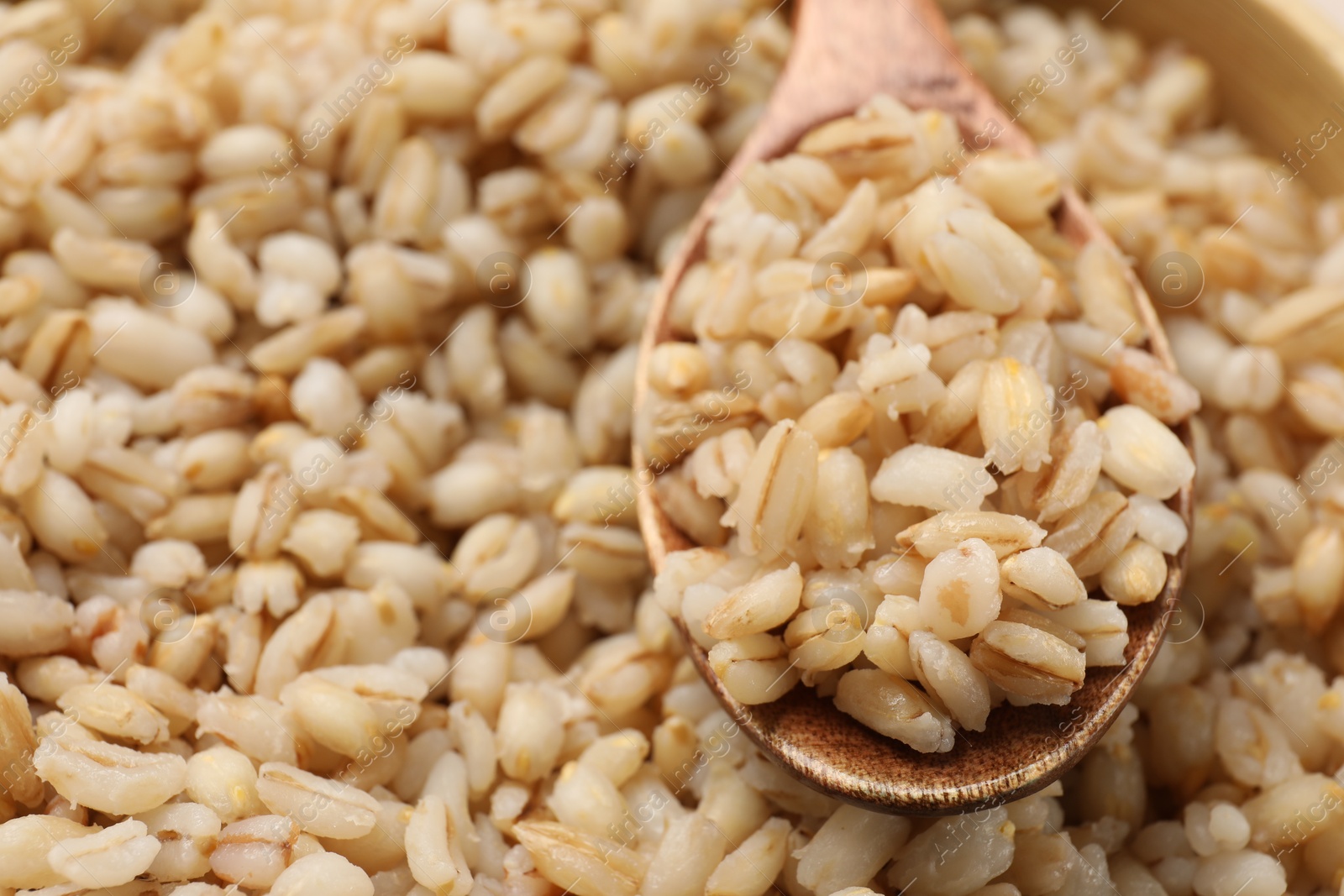 Photo of Delicious pearl barley and wooden spoon, closeup. Space for text