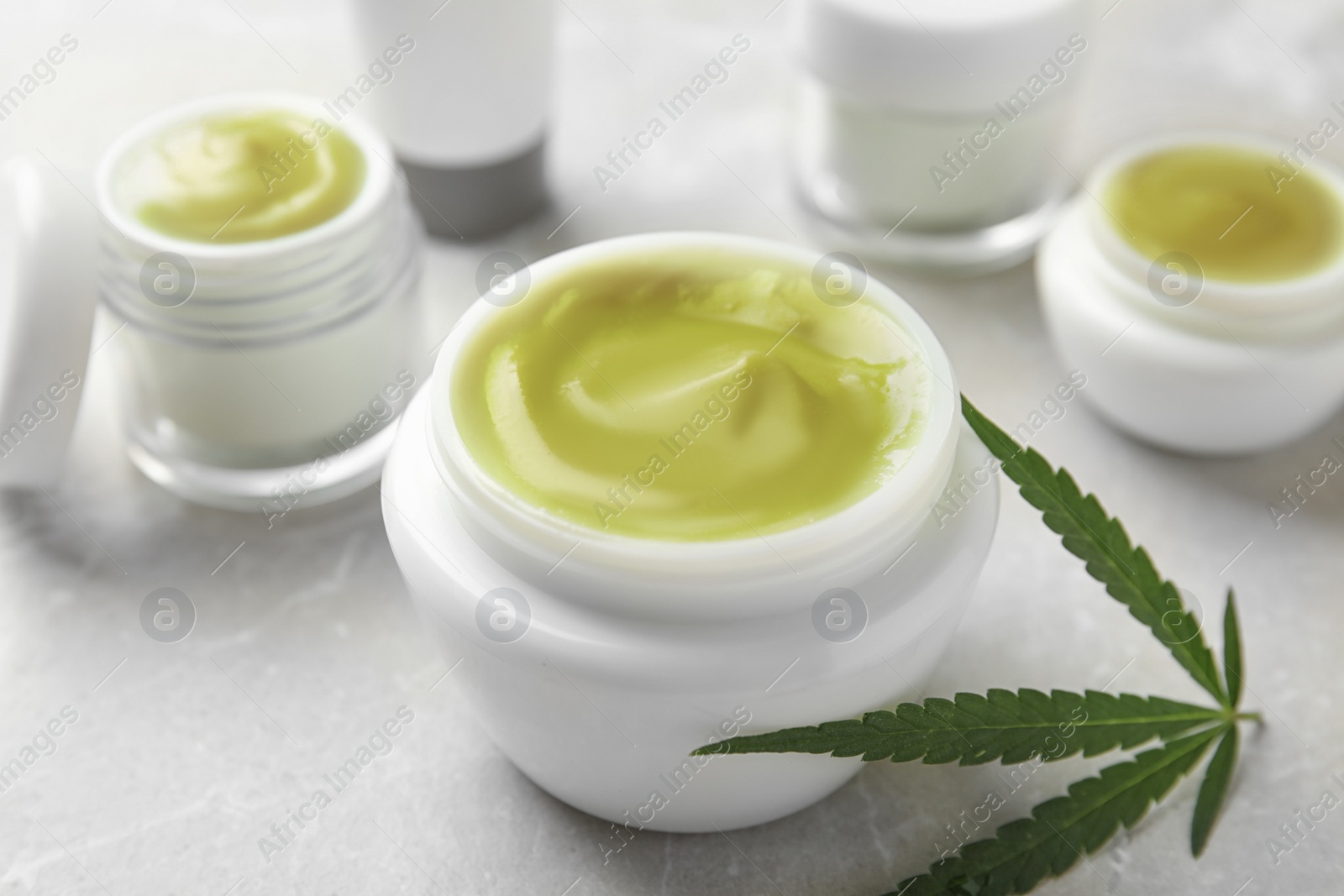 Photo of Composition with jar of hemp cream on grey table, closeup. Organic cosmetics