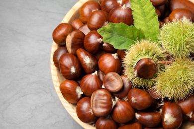 Photo of Fresh sweet edible chestnuts on black slate table, top view
