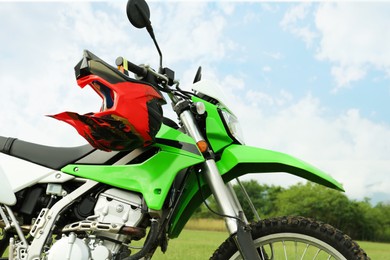 Stylish green cross motorcycle with helmet outdoors