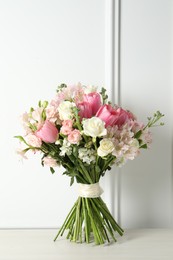 Photo of Beautiful bouquet of fresh flowers on table near white wall