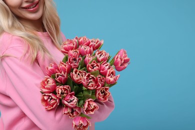 Photo of Happy woman holding beautiful bouquet on light blue background, closeup. Space for text