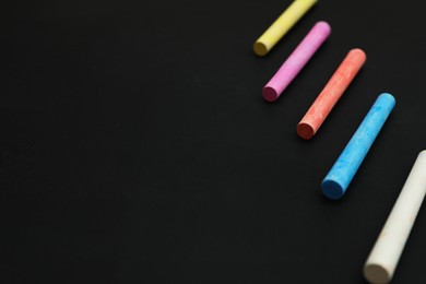Photo of Colorful chalks on black board, space for text