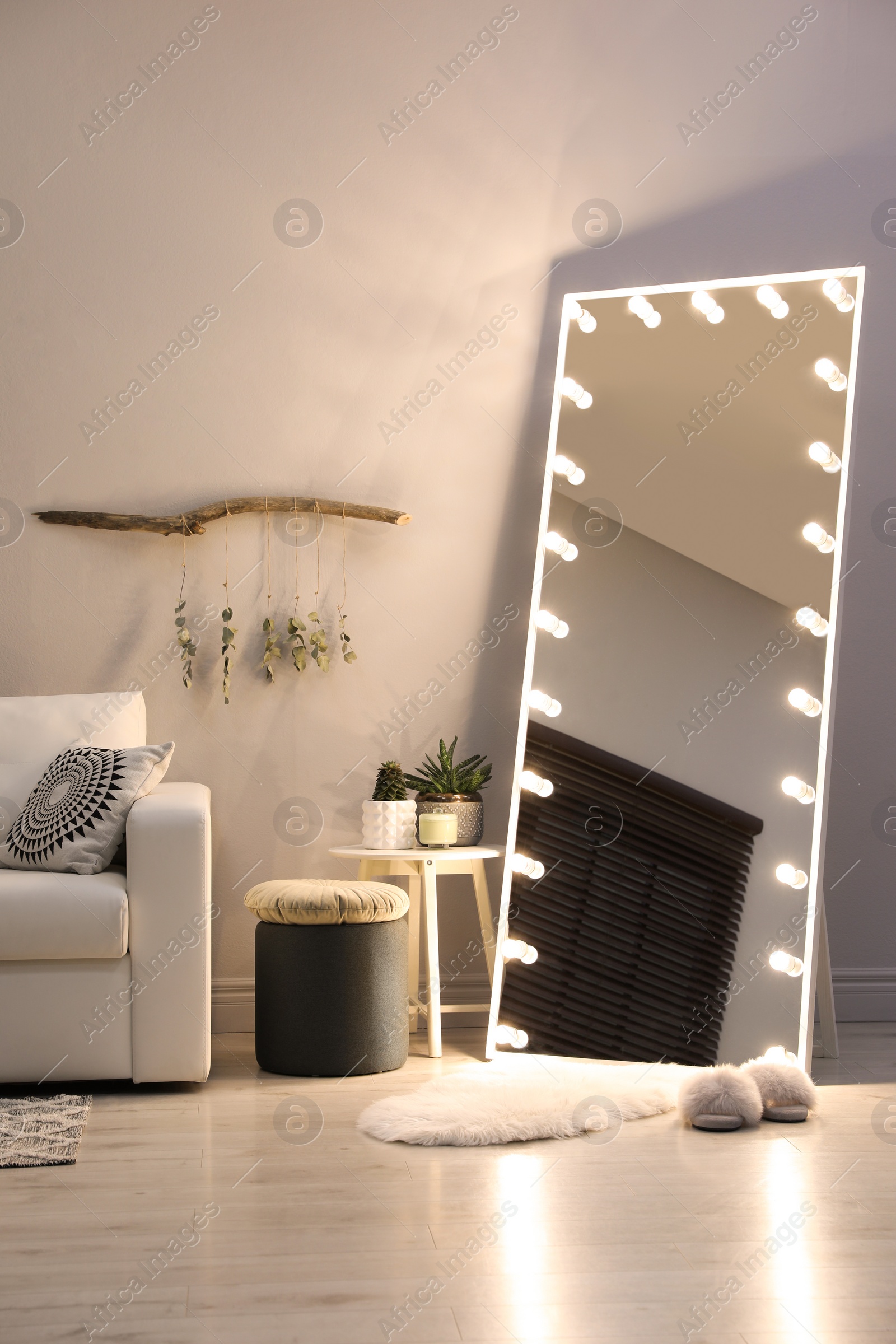 Photo of Stylish mirror with light bulbs and comfortable sofa in living room. Interior design