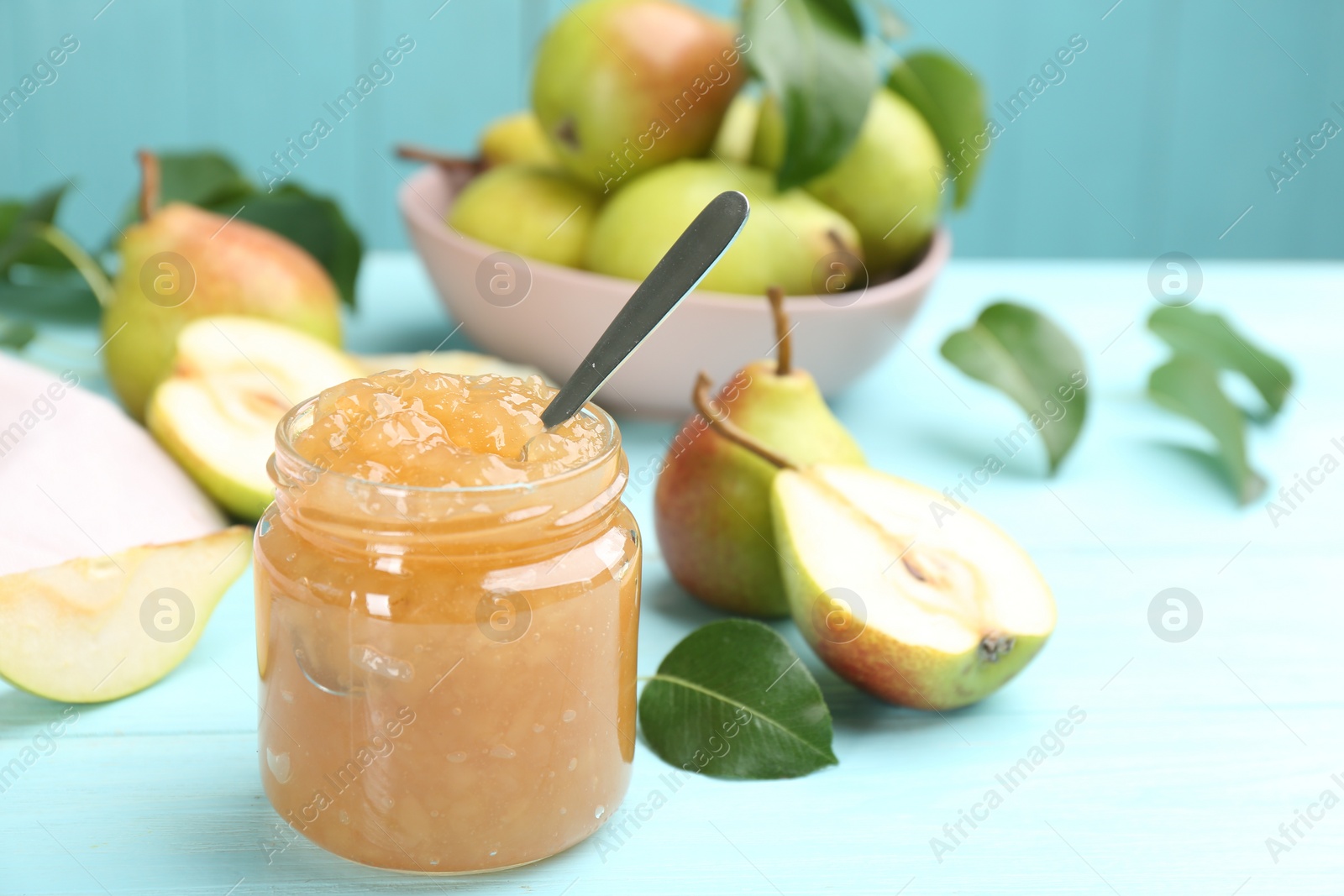 Photo of Tasty homemade pear jam and fresh fruits on light blue wooden table. Space for text