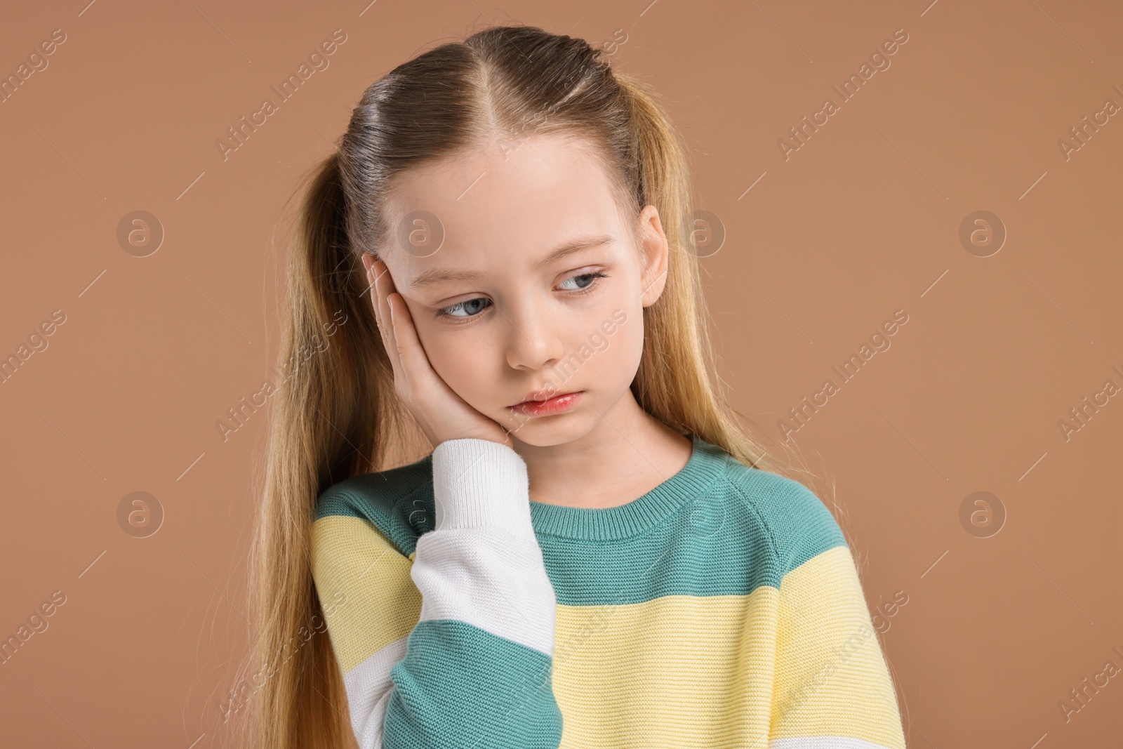 Photo of Portrait of sad girl on light brown background