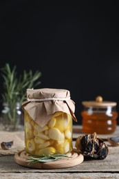 Garlic with honey in glass jar and fermented black garlic on wooden table