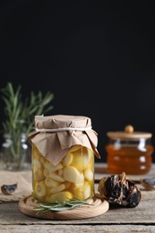 Photo of Garlic with honey in glass jar and fermented black garlic on wooden table