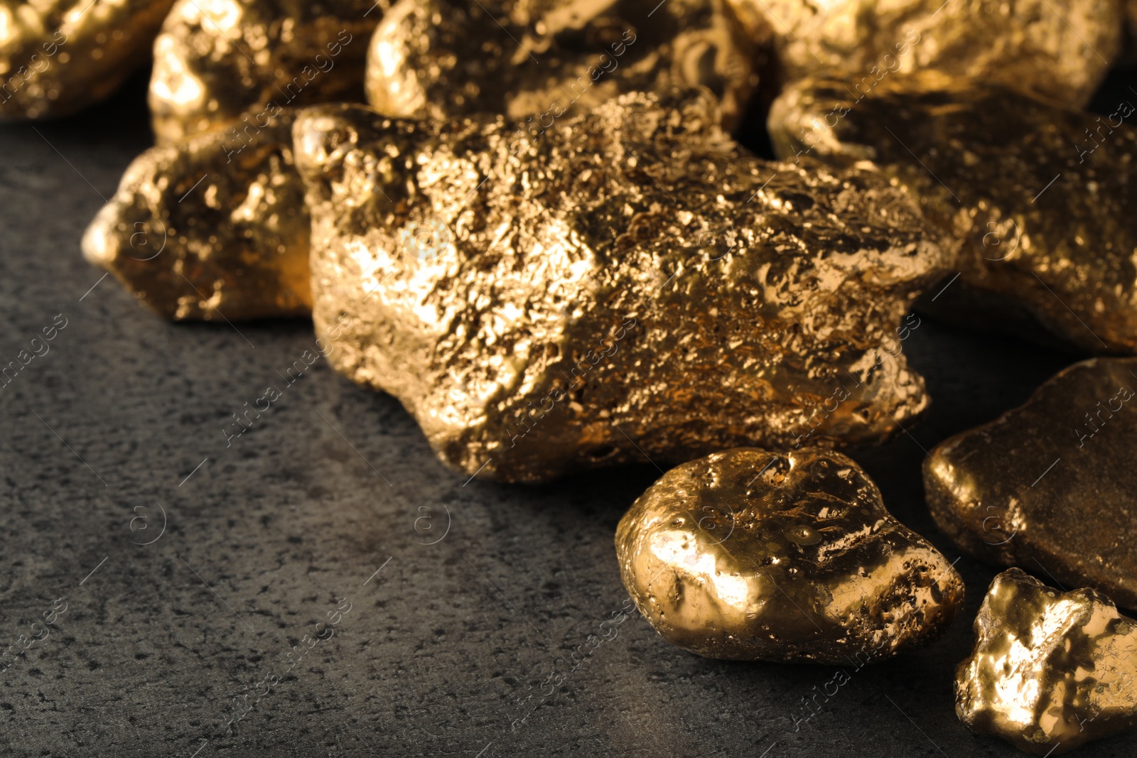 Photo of Pile of gold nuggets on grey table, closeup