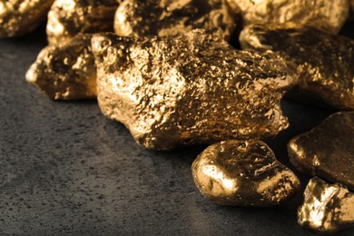 Photo of Pile of gold nuggets on grey table, closeup