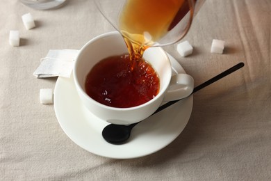 Photo of Pouring warm tea into cup on light table, closeup