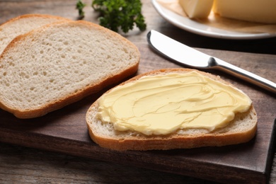 Photo of Tasty toast with butter and knife on wooden board