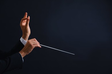 Photo of Professional conductor with baton on black background, closeup. Space for text