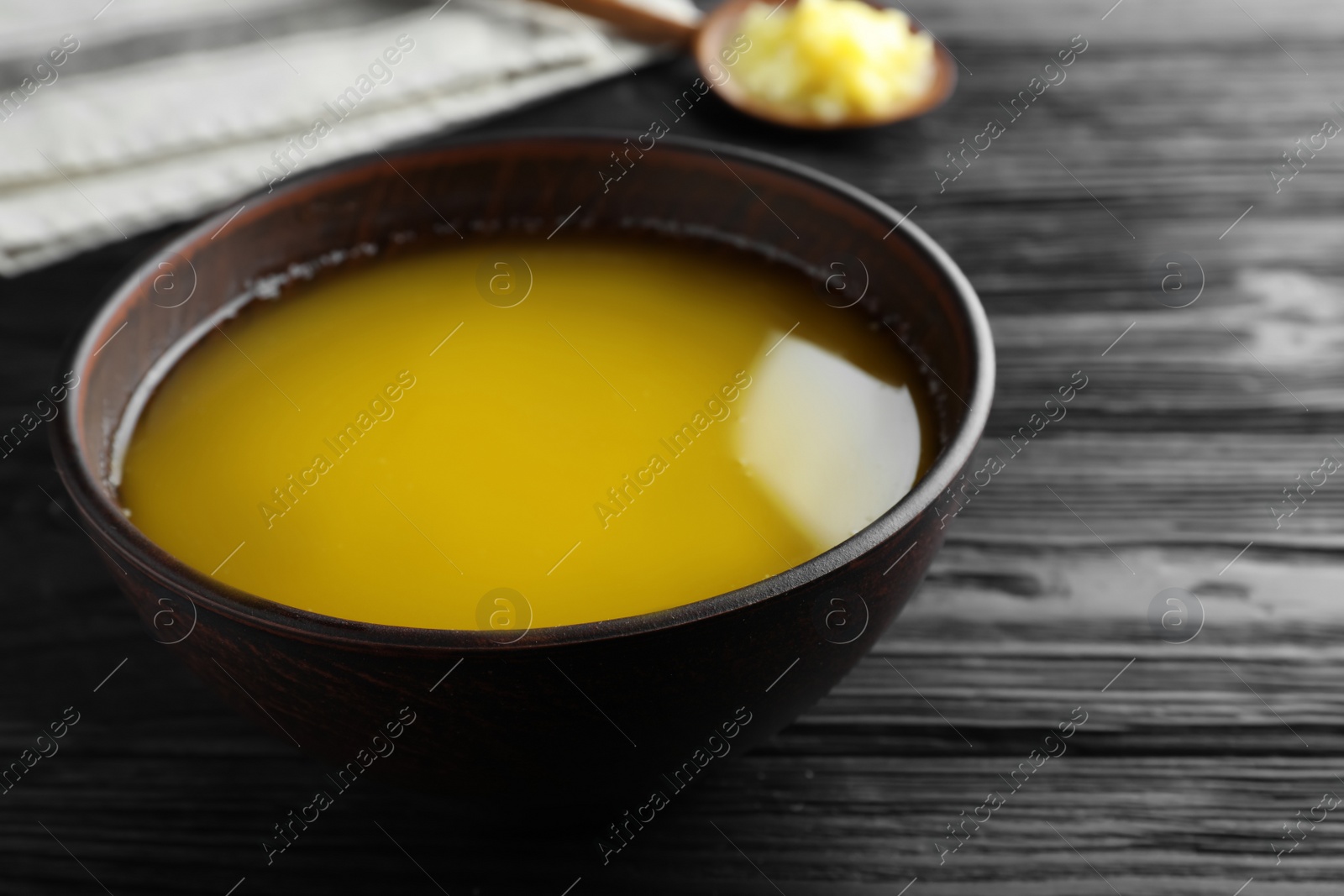 Photo of Bowl of Ghee butter on dark wooden table, closeup