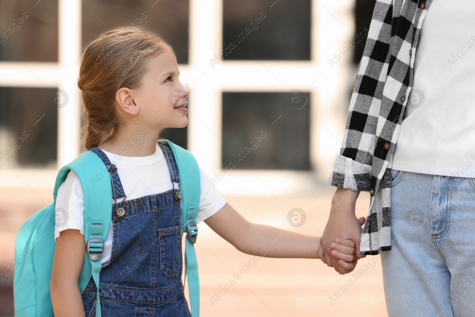 Photo of Little girl with backpack and her mother near school