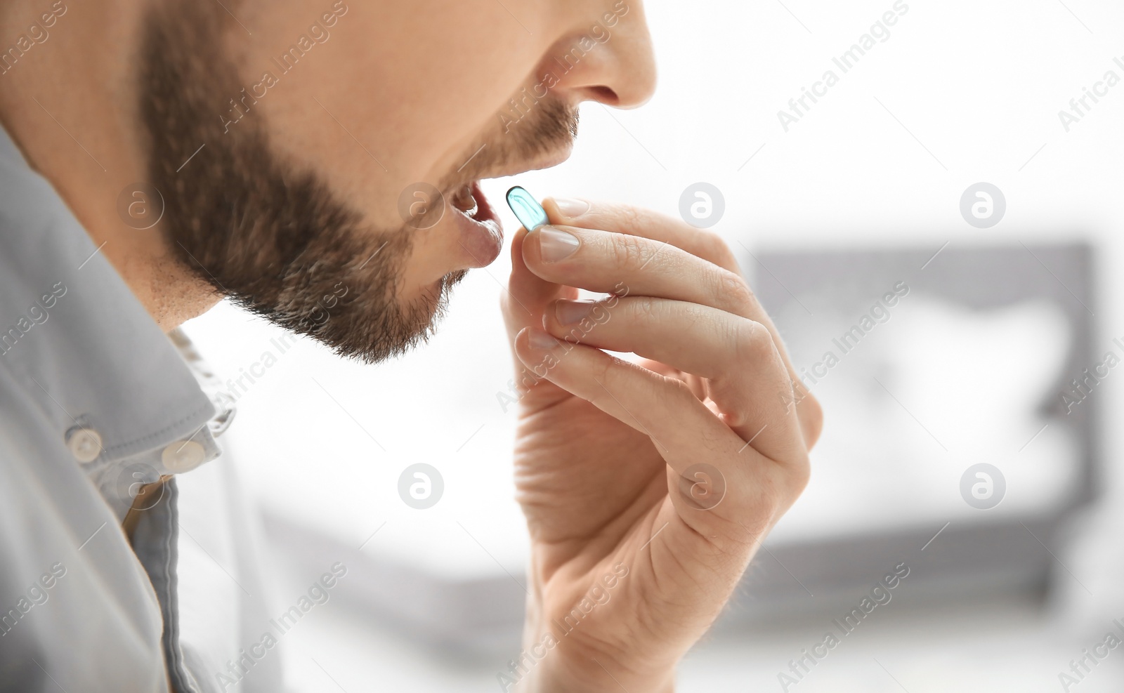 Photo of Young man taking pill indoors