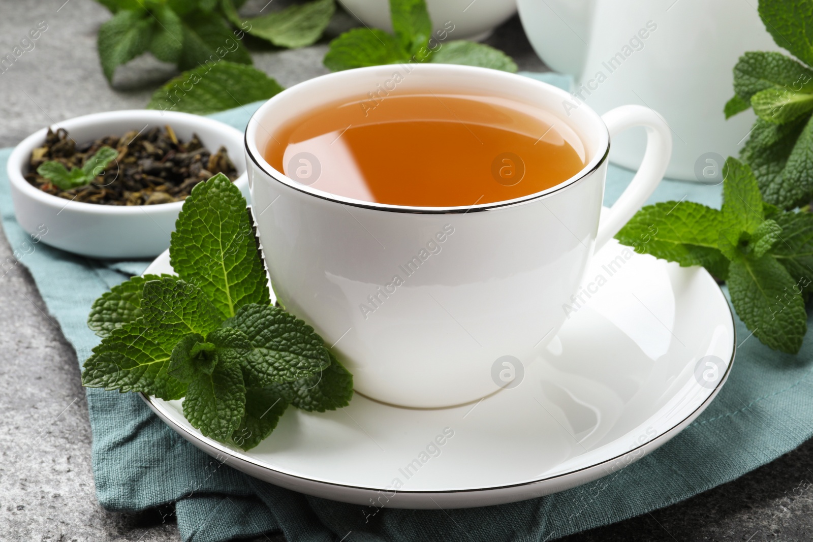 Photo of Cup of hot aromatic mint tea on grey table