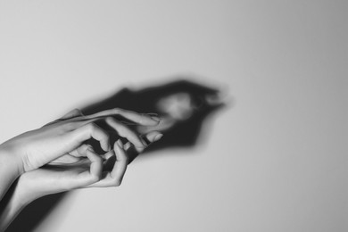 Photo of Shadow puppet. Woman making hand gesture like crocodile on light background, closeup with space for text. Black and white effect