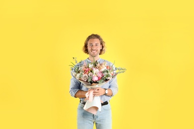 Photo of Young handsome man with beautiful flower bouquet on yellow background