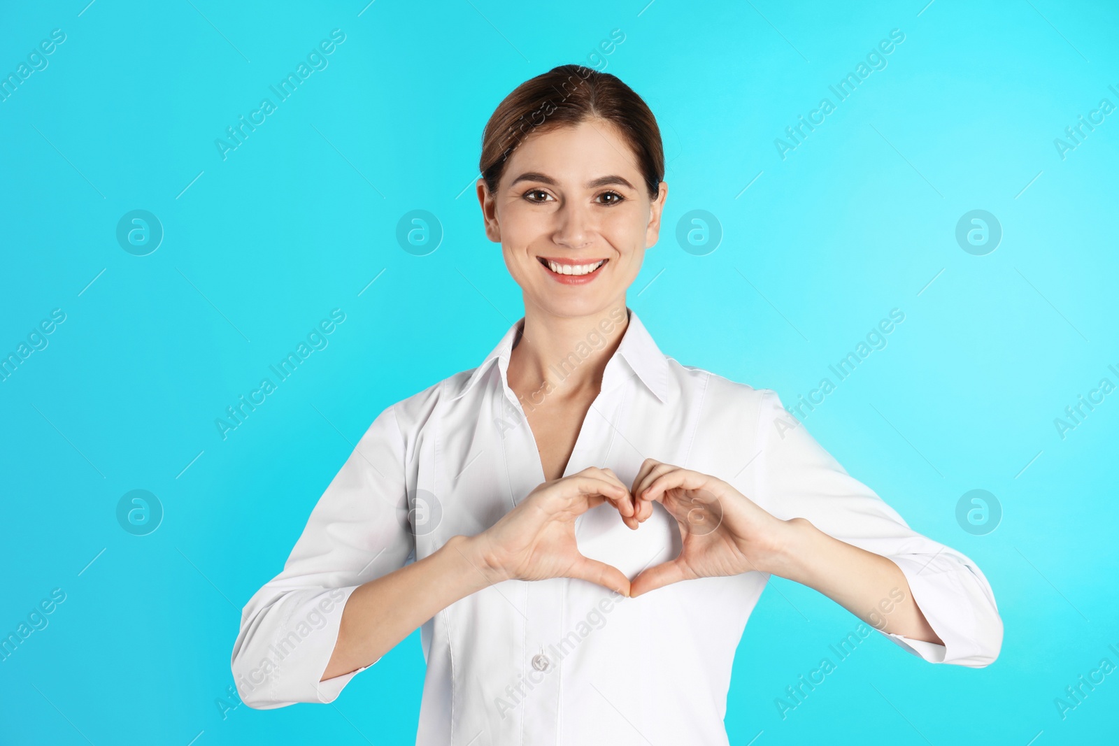 Photo of Portrait of woman making heart with her hands on color background