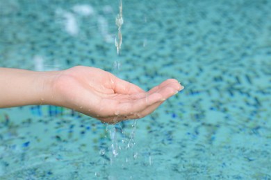 Water pouring into the girl's hand above pool, closeup