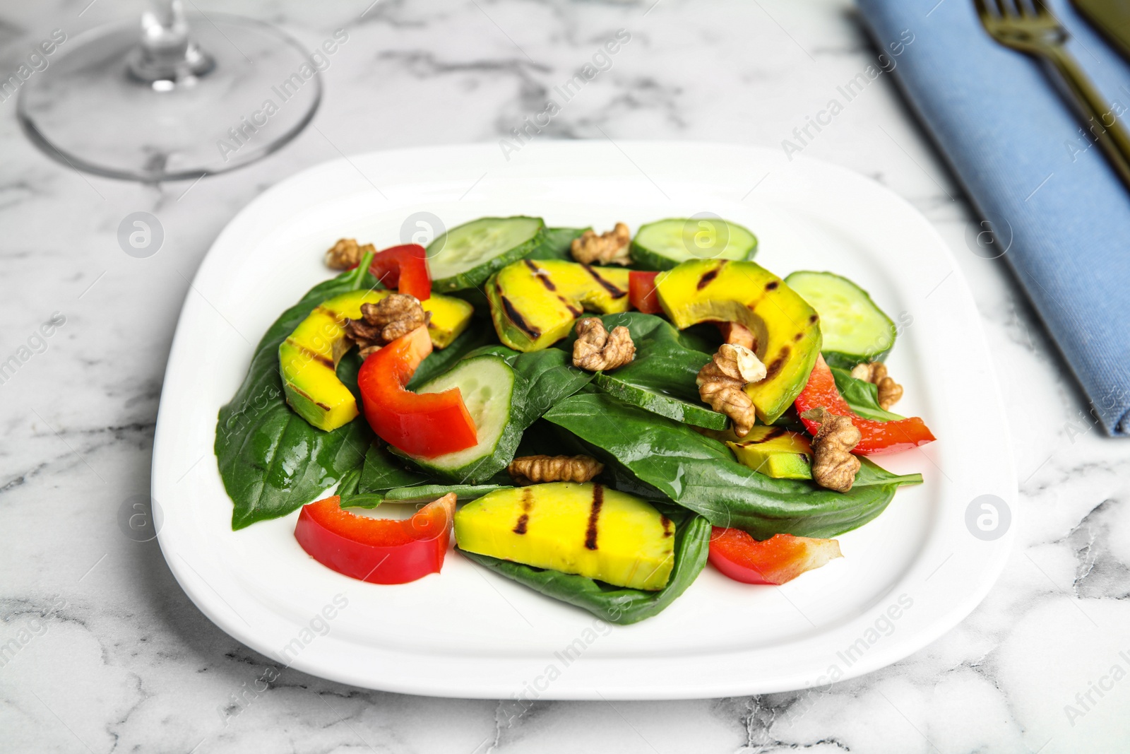 Photo of Delicious avocado salad served on marble table