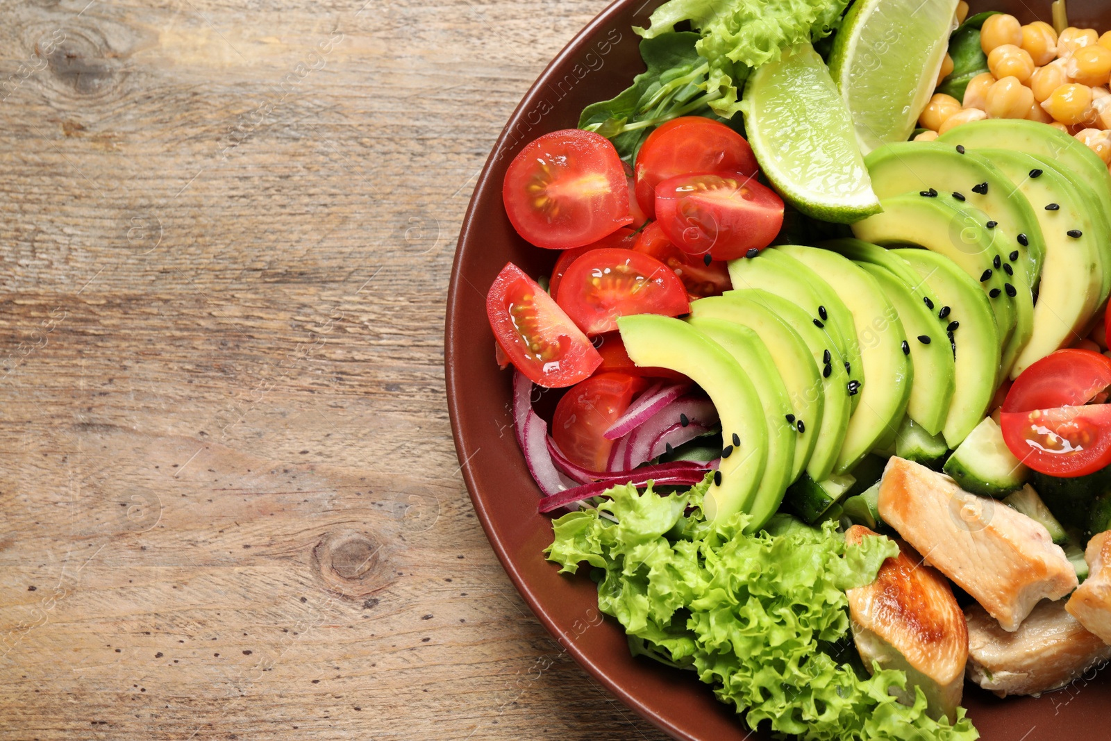 Photo of Delicious avocado salad with chicken on wooden table, top view. Space for text