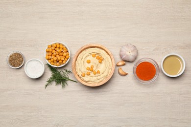 Bowl with delicious hummus and different ingredients on white wooden table, flat lay