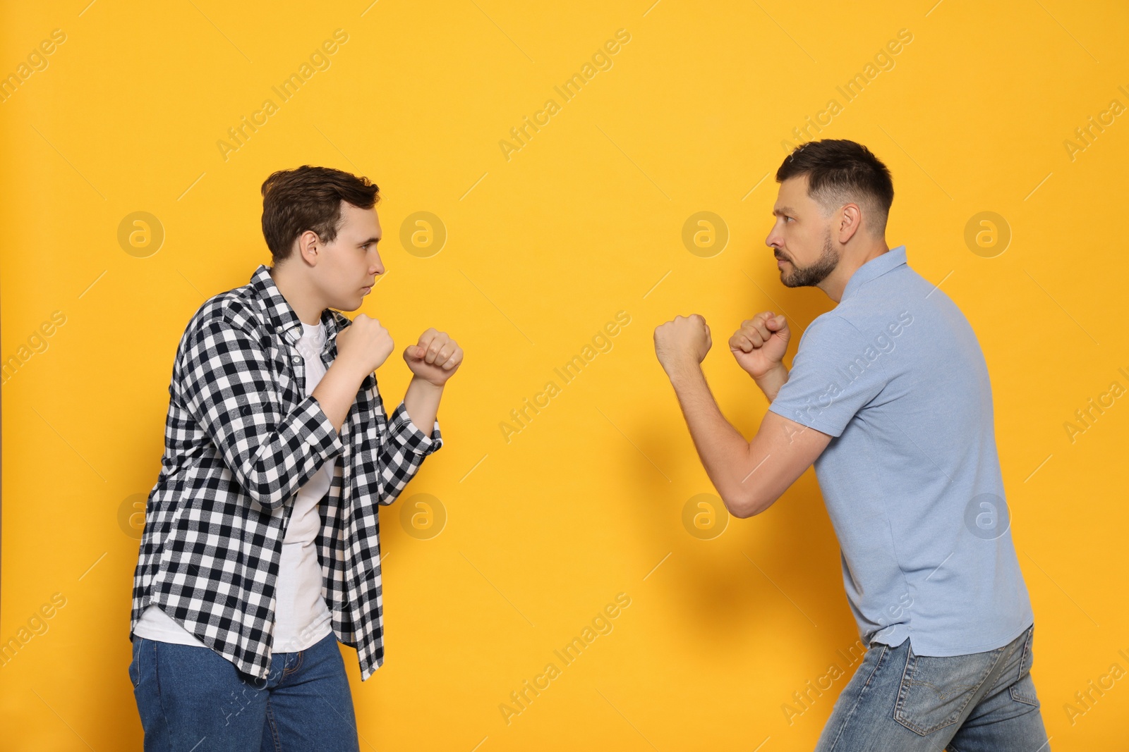 Photo of Two emotional men fighting on yellow background