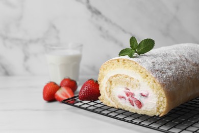 Photo of Delicious sponge cake roll with strawberries and cream on white table, space for text