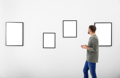 Young man viewing exposition in modern art gallery