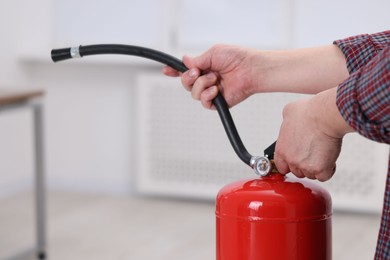 Photo of Man with one fire extinguisher indoors, closeup