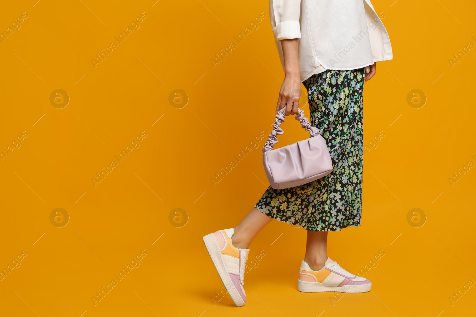 Photo of Stylish woman with trendy baguette bag on yellow background, closeup. Space for text