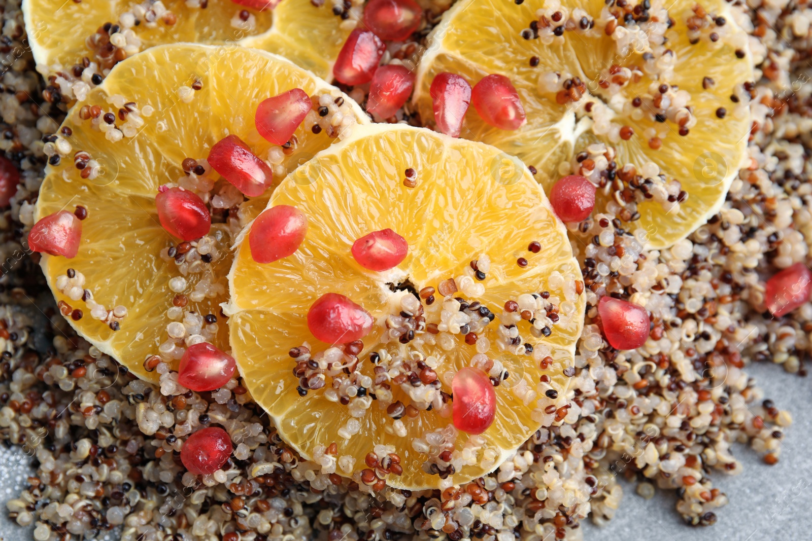 Photo of Quinoa porridge with orange and pomegranate seeds on plate as background, top view