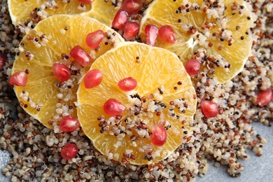 Photo of Quinoa porridge with orange and pomegranate seeds on plate as background, top view
