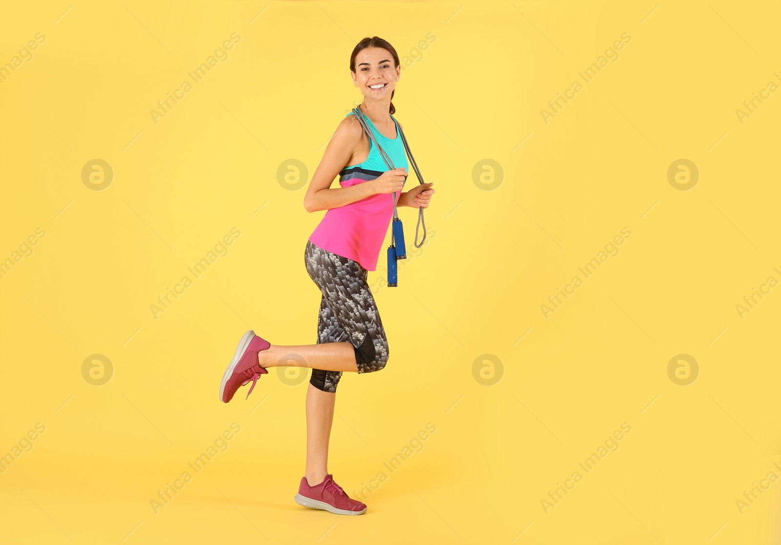 Photo of Full length portrait of young sportive woman with jump rope on color background