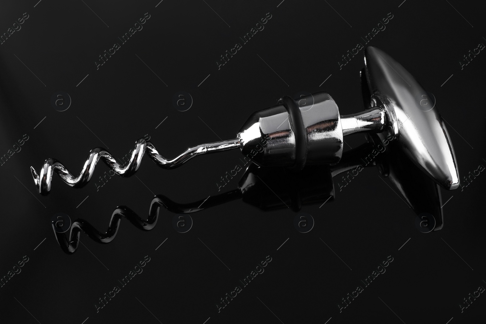 Photo of One metal corkscrew on dark mirror surface, closeup