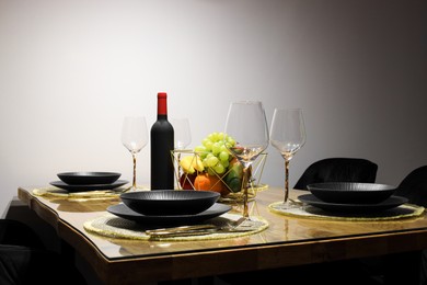 Photo of Table with plates, fruits, glasses and bottle of wine in room