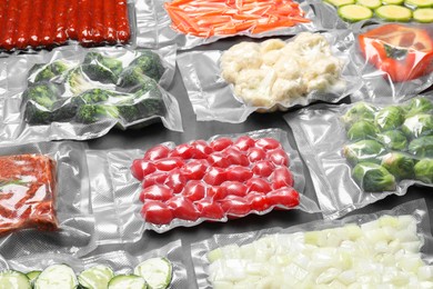 Photo of Many different food in vacuum packings on dark grey table, closeup